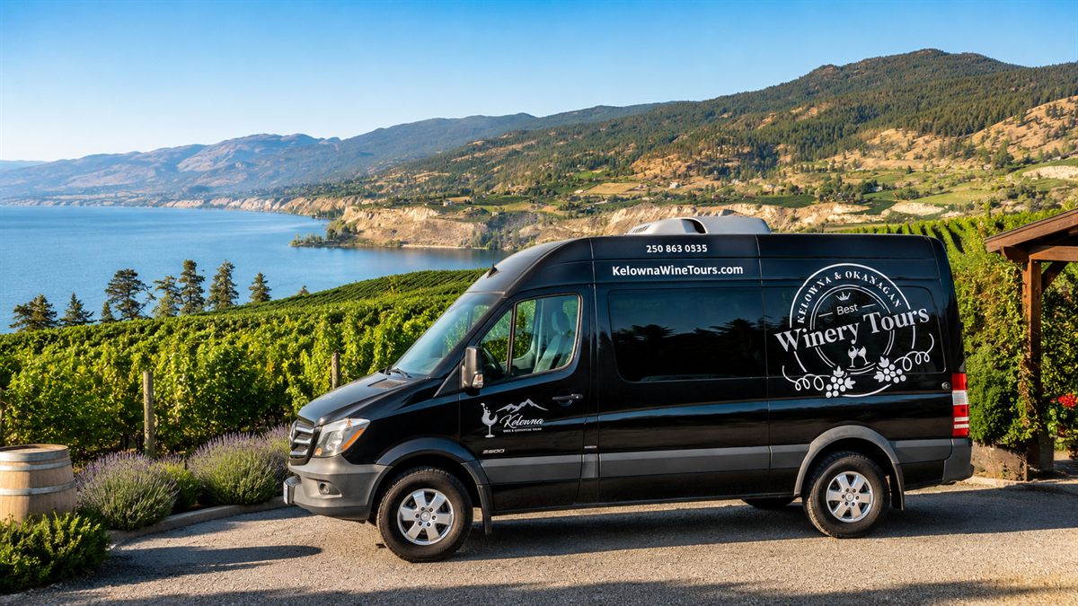 Kelowna Wine Tours van parked above Okanagan vineyards and Okanagan Lake